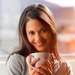 sunrise coffee woman Woman drinking coffee at home with sunrise streaming in through window and creating flare into the lens.